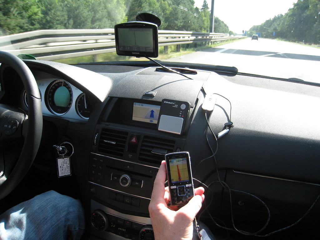Driver using smartphone-based GPS car tracking system for live navigation and fleet monitoring on a highway in 2026
