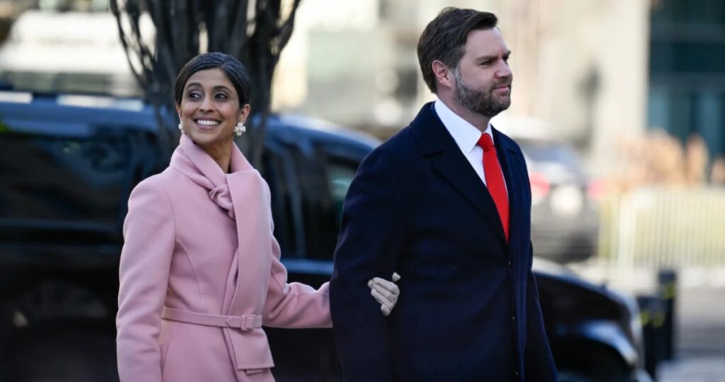 Usha Vance, Second Lady of the United States, smiling and gently cradling her baby bump, with a blurred Capitol and American flag background.