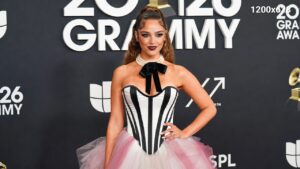 Chappell Roan on the red carpet at the 2026 Grammys, wearing a glamorous maroon high-fashion gown, with sparkling lights and elegant silhouette.